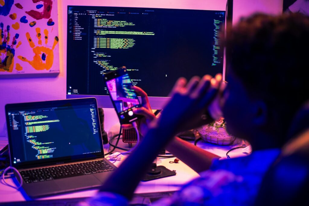 Indie-Spiel entwickeln: Entwickler programmiert nachts an mehreren Bildschirmen